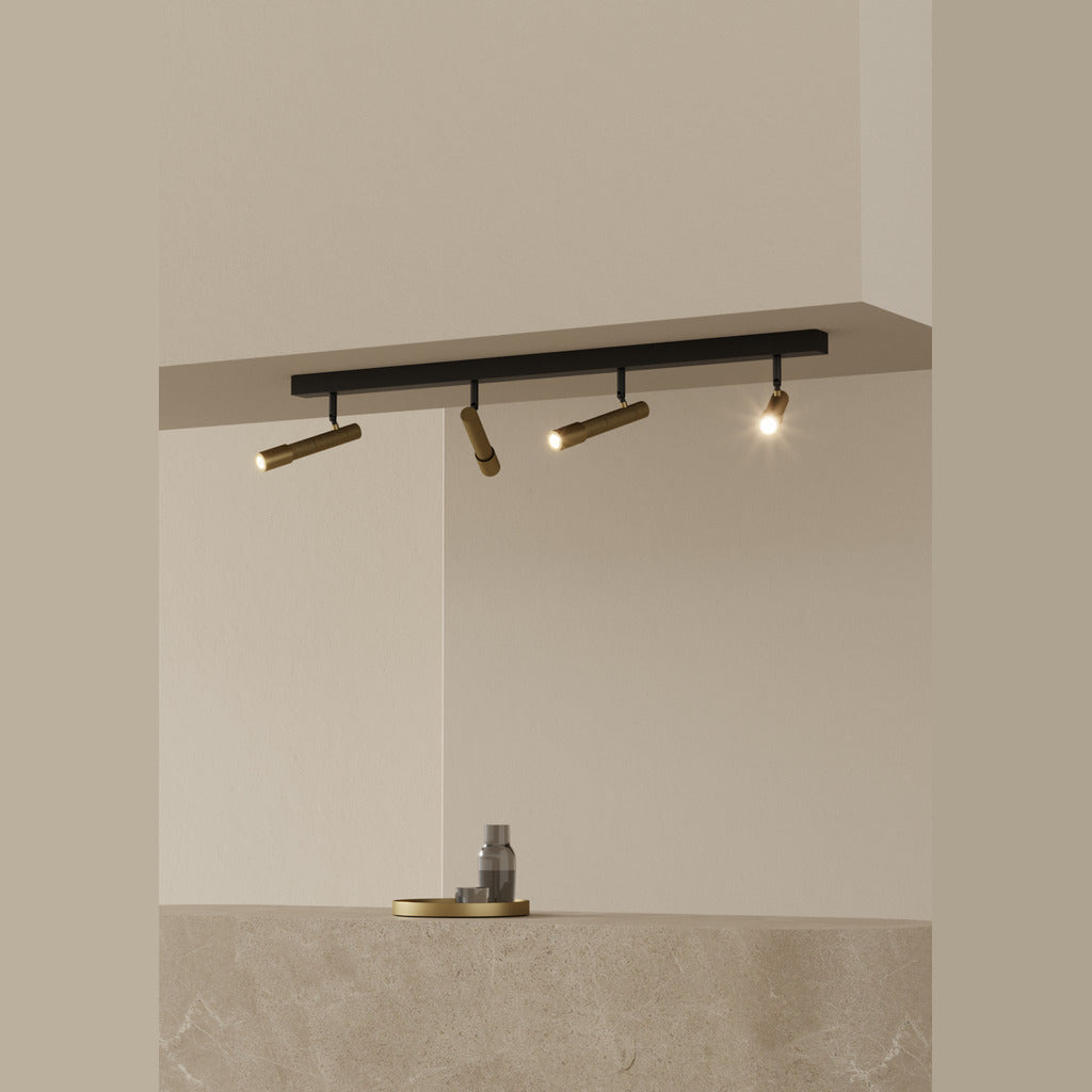Ycro Spot black bar with gold spotlights lit, angled over a stone counter in a beige interior