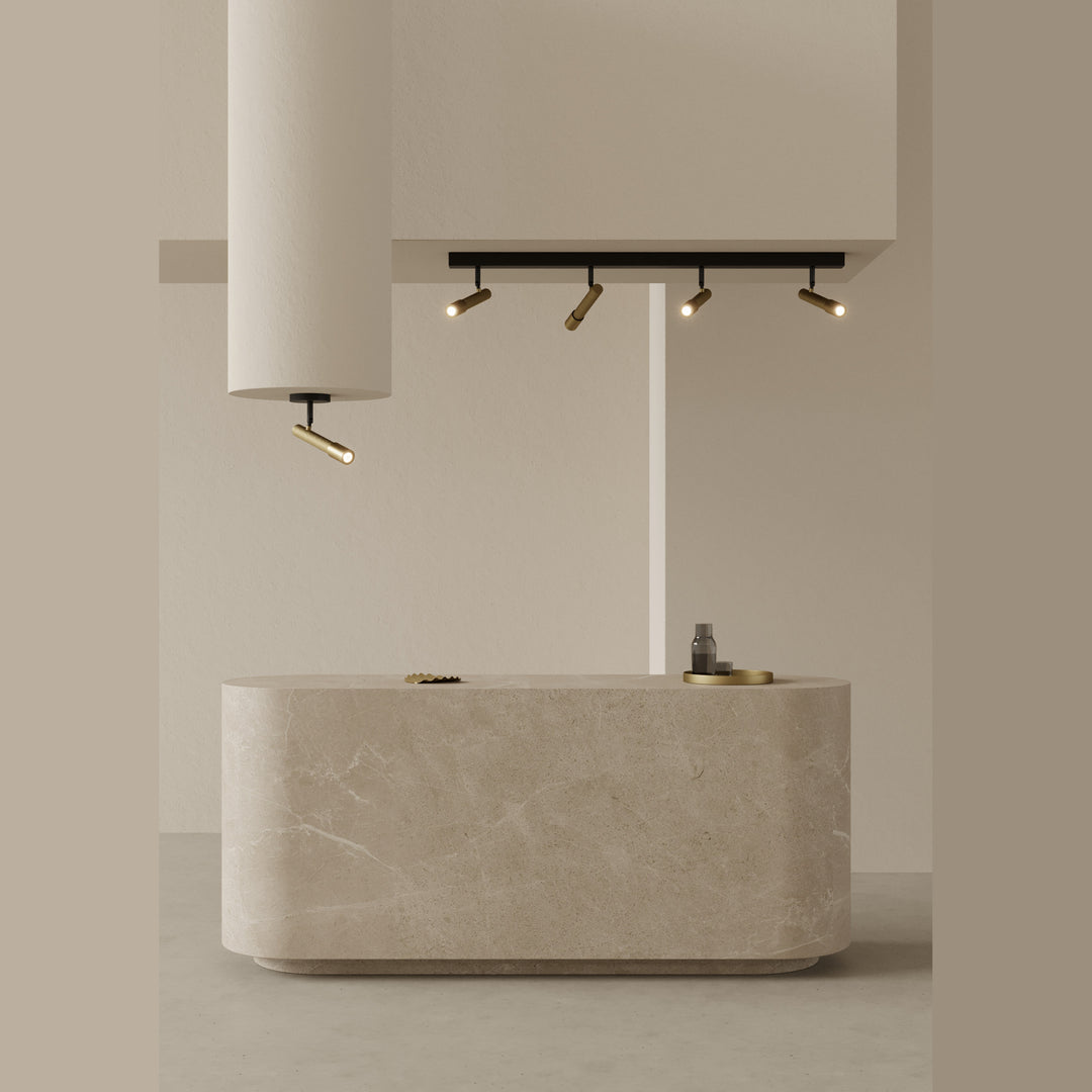 Ycro Spot with gold spotlights on a black bar lit above a curved stone reception counter