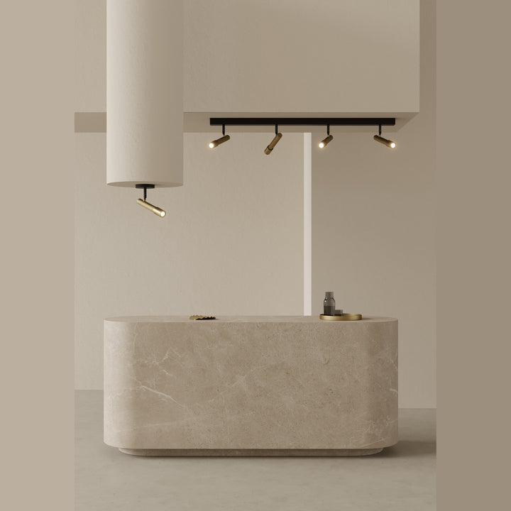 Ycro Spot with gold spotlights on a black bar lit above a curved stone reception counter