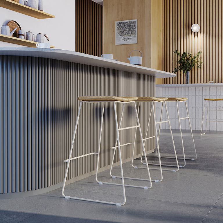 Modern bar stools with woven seats and white metal frames, styled in a minimalist kitchen with wood slat walls.