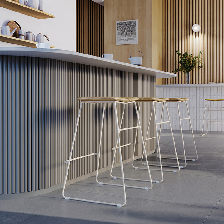 Modern bar stools with woven seats and white metal frames, styled in a minimalist kitchen with wood slat walls.
