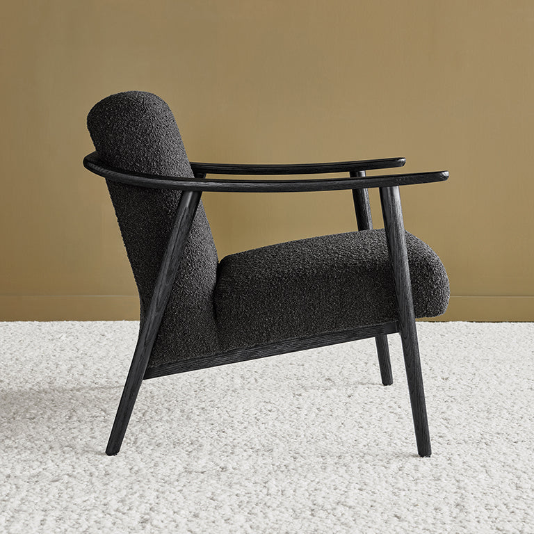 Black bouclé armchair with sleek wooden frame, modern designer furniture
