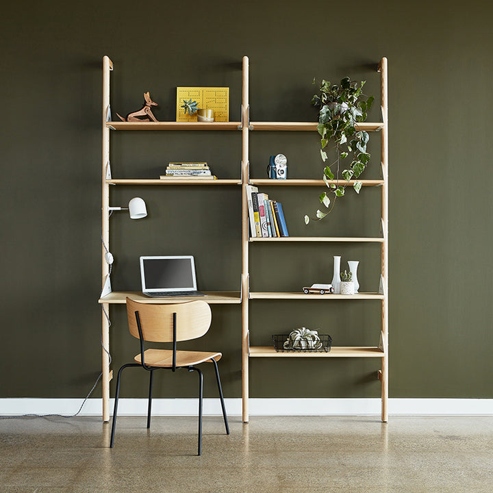 Minimalist oak shelving unit with integrated desk, styled with books, plants, and decor