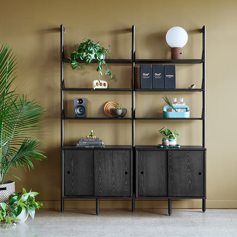 Black metal shelving unit with wood grain cabinets, styled with plants and decor