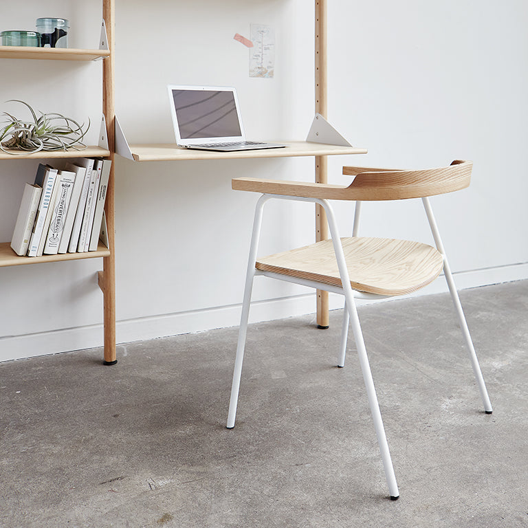 Modern oak chair with white metal legs, paired with minimalist desk and shelving