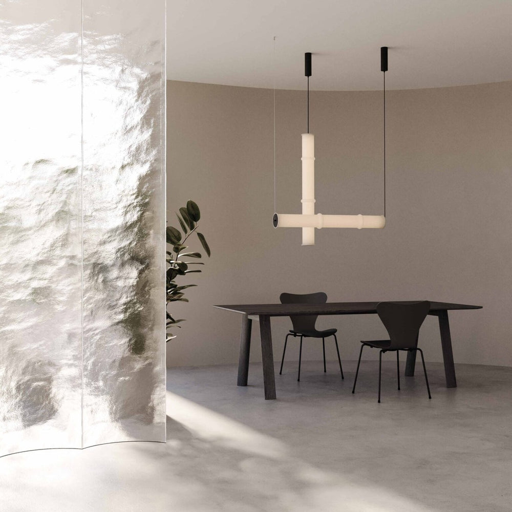 Canna Large Pendant Lamp lit above a black dining table and chairs beside a textured glass screen