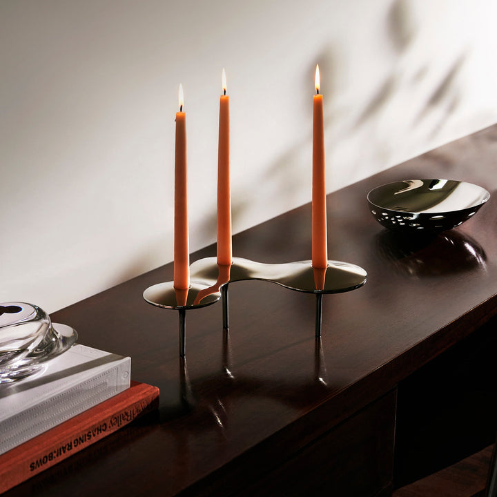 Cell Candle Holder — large silver piece with three lit orange tapered candles on a dark wood console