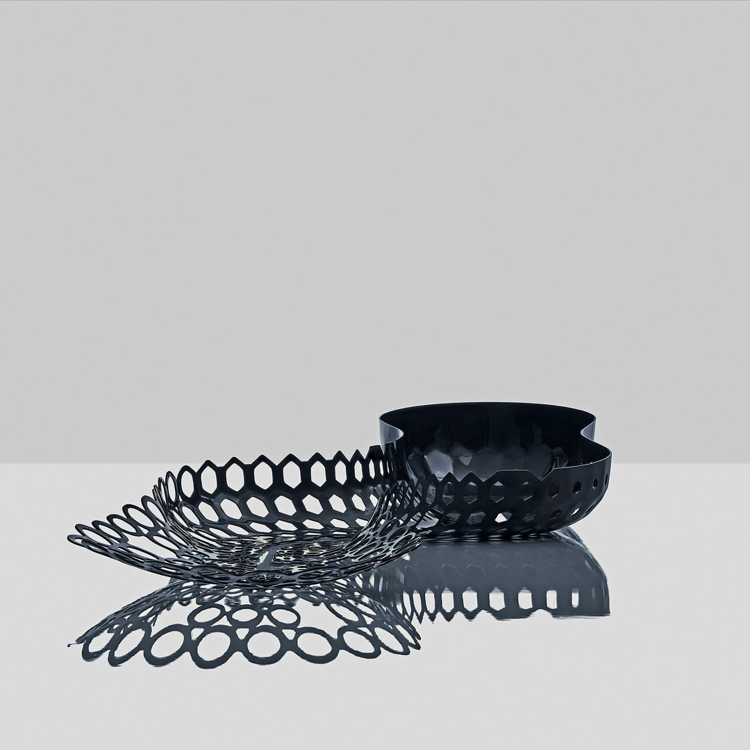 Cell Centerpiece — black centerpiece with its perforated cells reflected on a glossy gray surface
