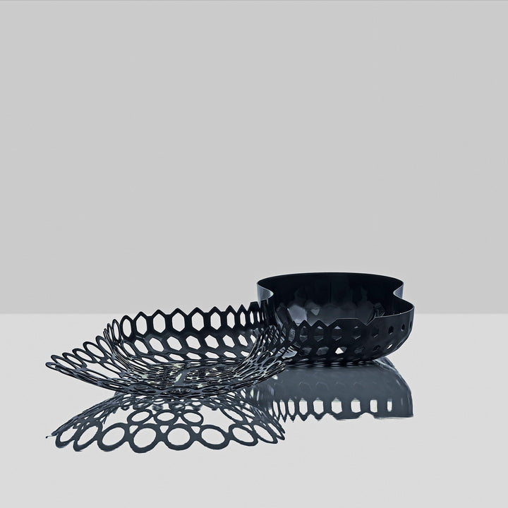 Cell Centerpiece — black centerpiece with its perforated cells reflected on a glossy gray surface