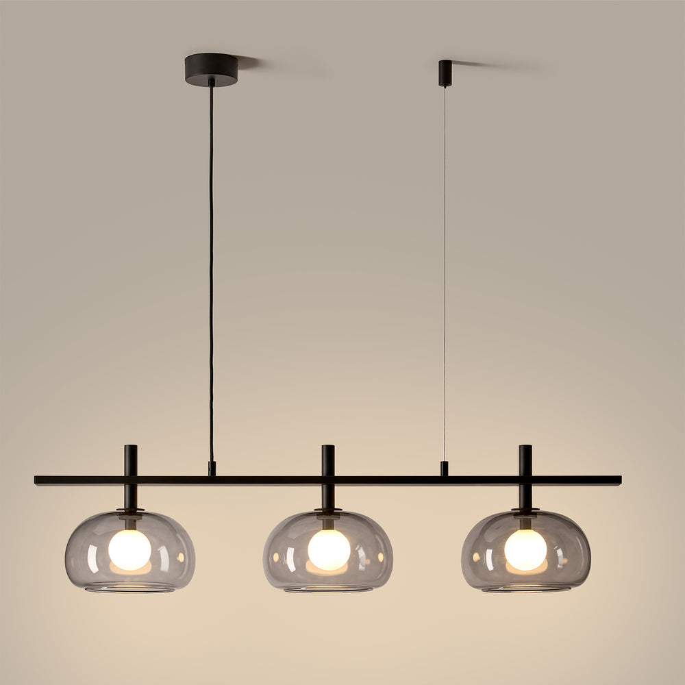 Cloud Big Linear Pendant lit, three glowing smoked glass shades on a black bar against a warm wall