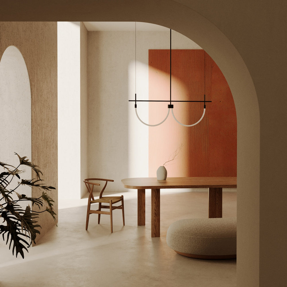 Cram Double Linear Pendant above a wooden dining table with a wishbone chair, arched walls and terracotta panel