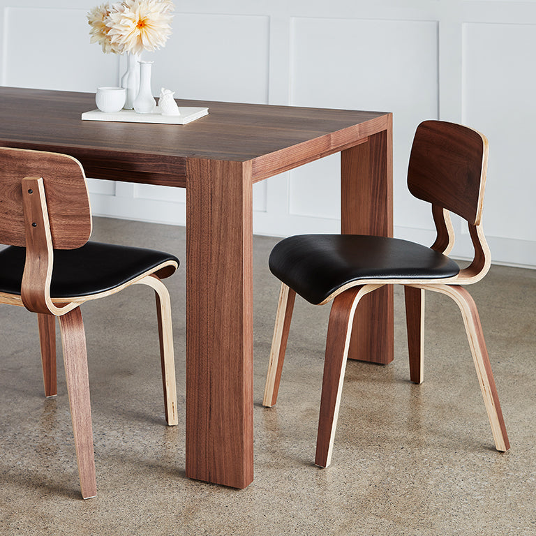 Walnut dining table with sculpted wood chairs and black leather seats