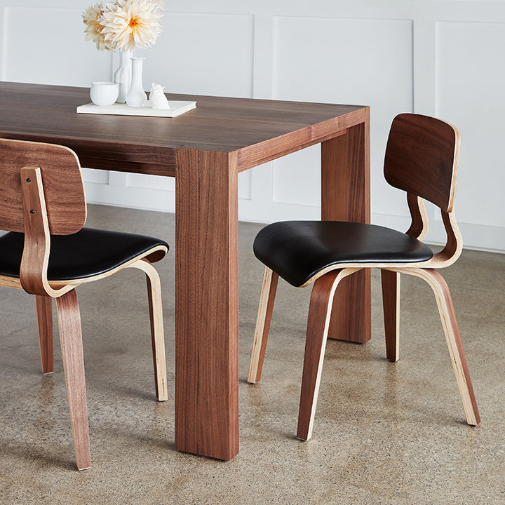 Walnut dining table with sculpted wood chairs and black leather seats