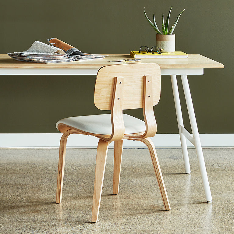 Scandinavian-style bentwood chair with white upholstered seat, paired with minimalist desk and olive wall