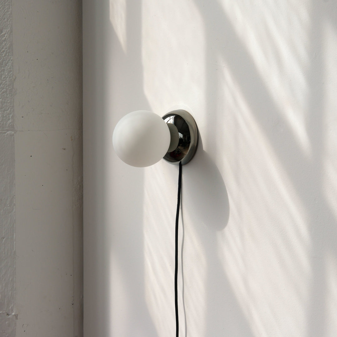Matte glass globe wall sconce with polished chrome base, minimalist modern lighting design