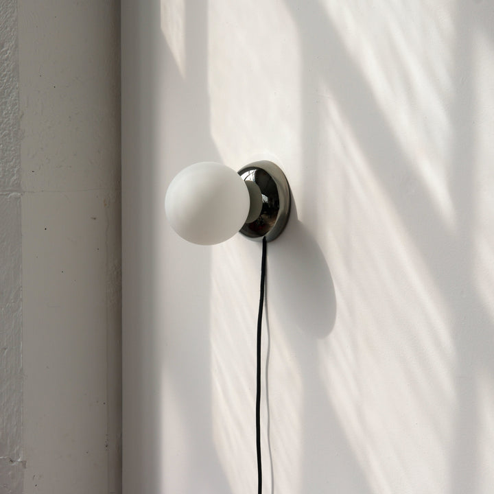 Matte glass globe wall sconce with polished chrome base, minimalist modern lighting design