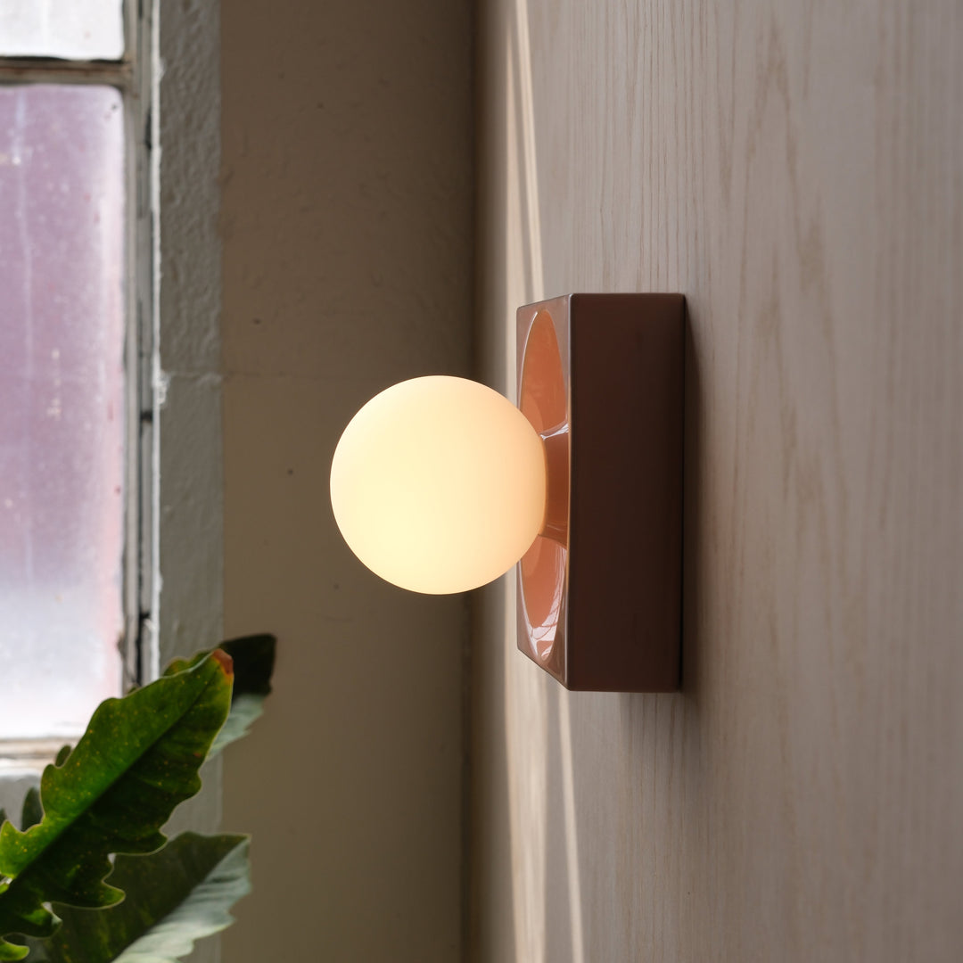 Globe wall sconce with matte ceramic base, modern minimalist lighting for contemporary interiors