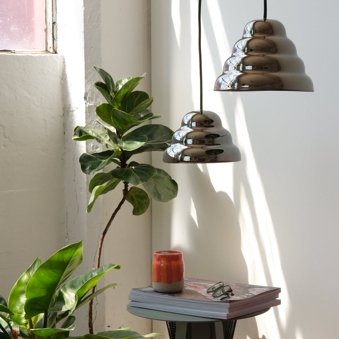 Chrome tiered pendant lights with fiddle leaf fig and ceramic vase on side table