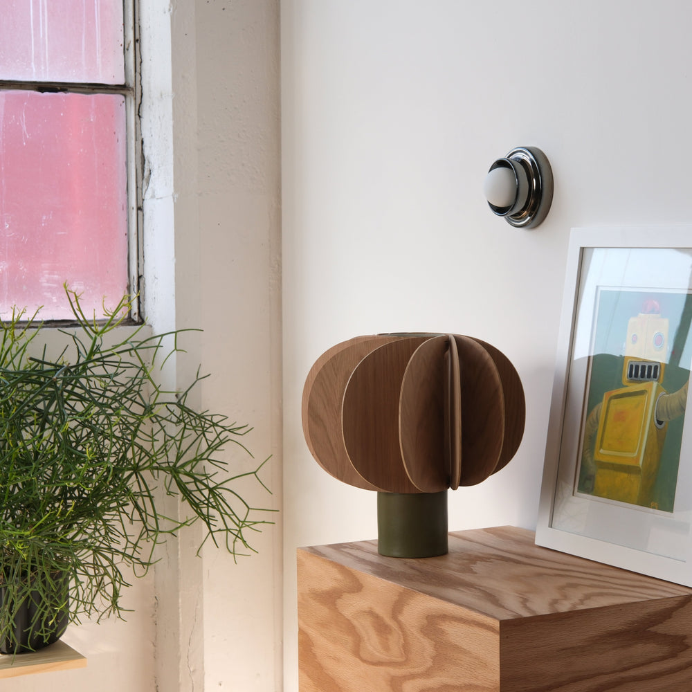 Walnut sculptural vase with olive base, styled beside framed art and greenery