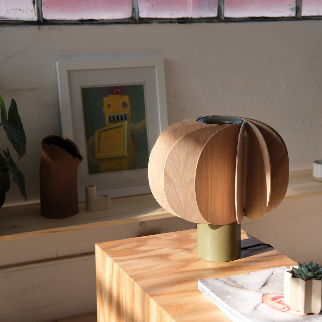 Scandinavian oak table lamp with petal design, olive base, styled on wooden console