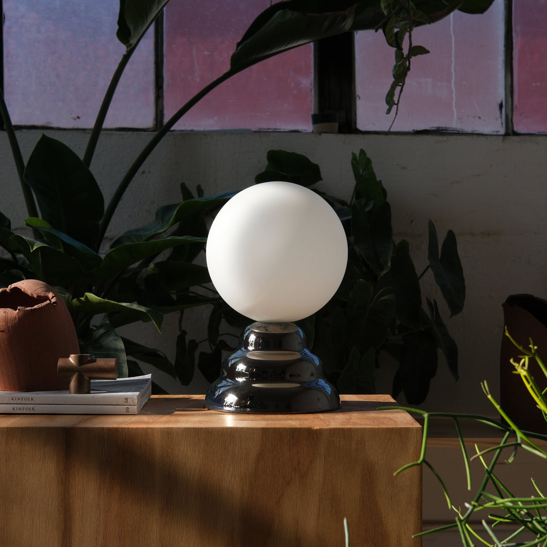 Sleek chrome base table lamp with frosted glass globe, styled with Kinfolk books and greenery
