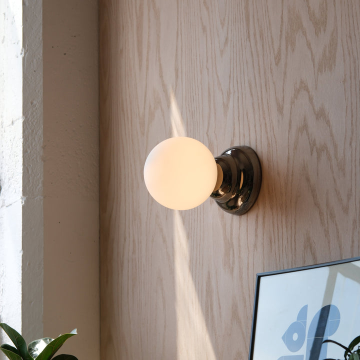 Sleek chrome sconce with frosted glass globe, modern wall lighting