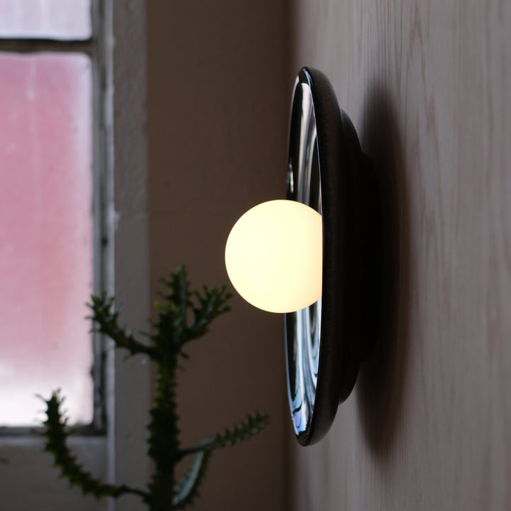 Sleek black ceramic wall sconce with glowing orb, modern designer lighting