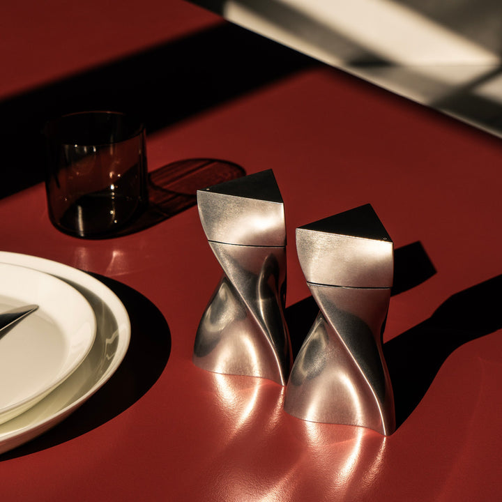Duo Mini Salt and Pepper Grinder Set — All Silver grinders on a red table beside plates, lifestyle