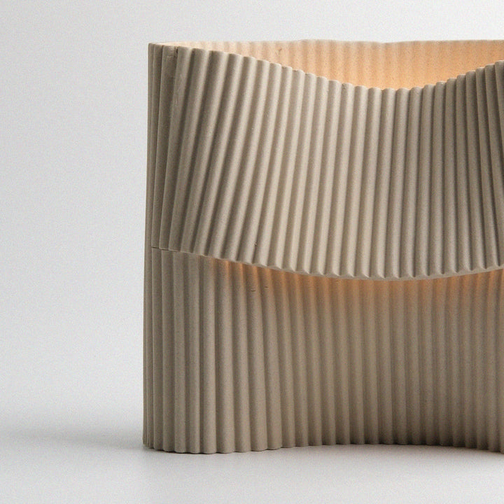 Rippled concrete planter with minimalist design and warm interior glow
