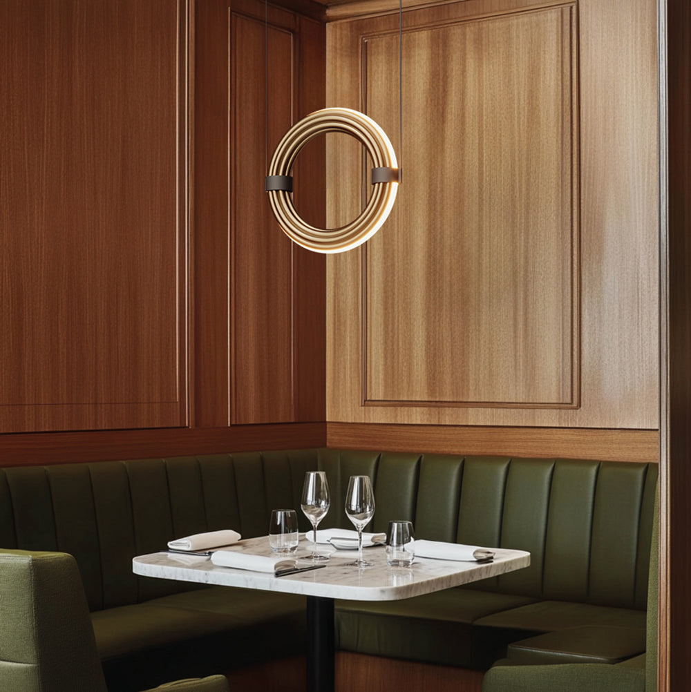 Elli Pendant Lamp, a lit gold ring pendant over a marble bistro table and green banquette, by Aromas del Campo