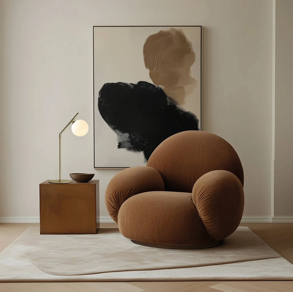 Brass Endo Table Lamp lit on a wooden side table beside a rounded brown armchair