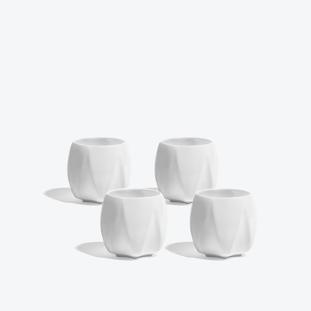 Folio Vessel, Set of 4 — four small white faceted porcelain vessels arranged on a white background