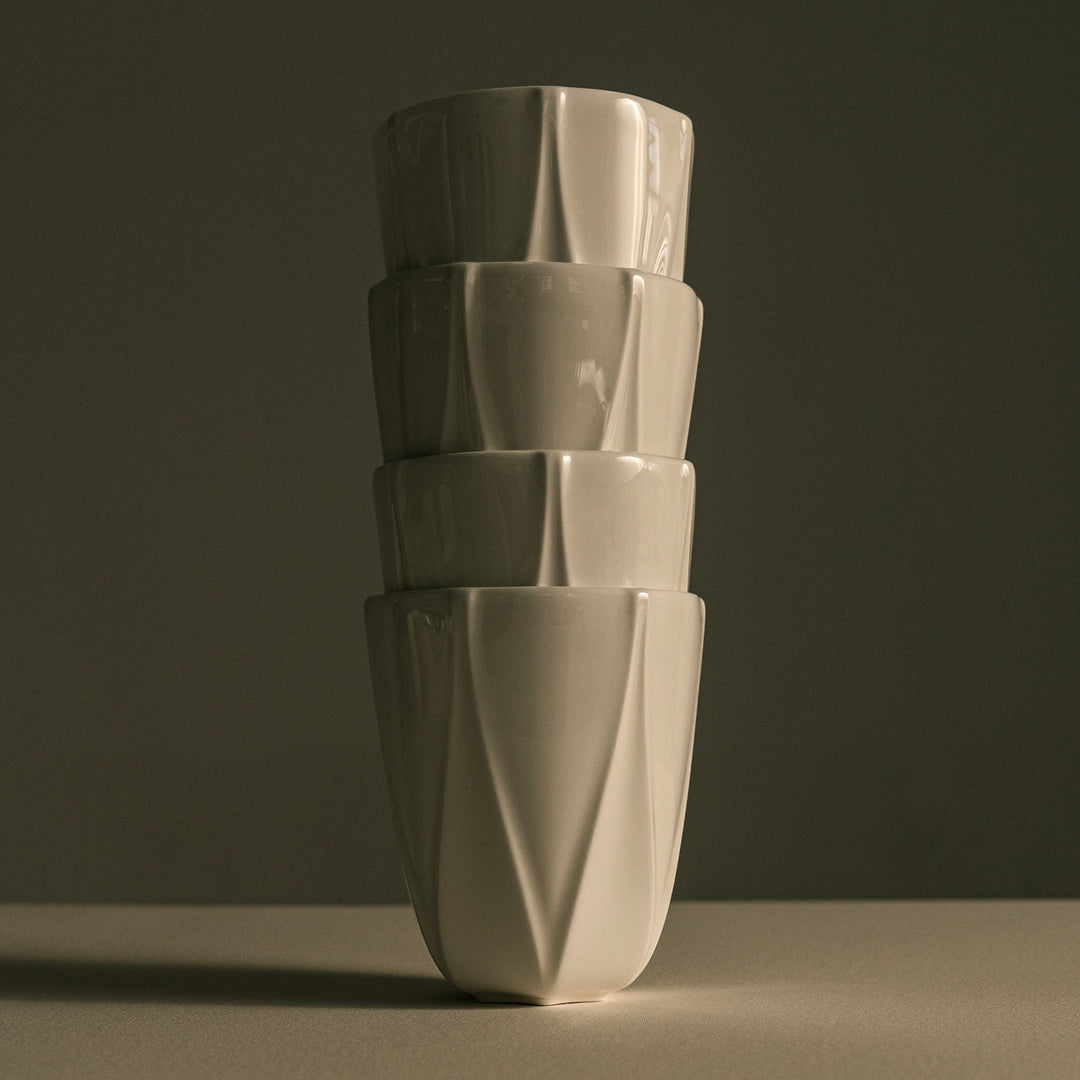 Folio Vessel, Set of 4 — white faceted vessels stacked in a column against a dark backdrop