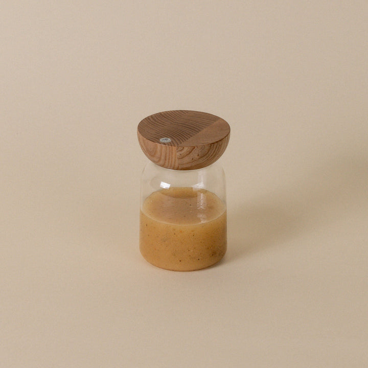 Glass bottle with wooden cap on a beige background