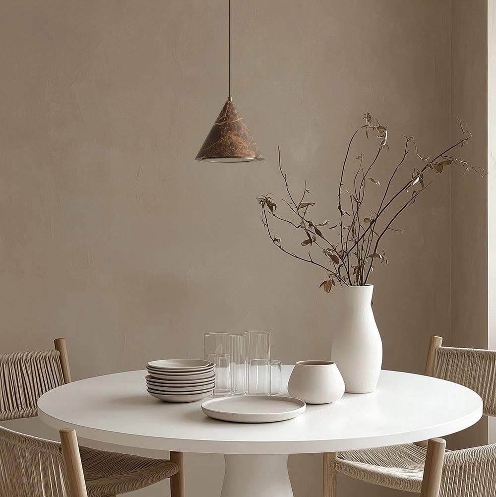 Iconic Pendant Lamp over a round white dining table with a vase of dried branches