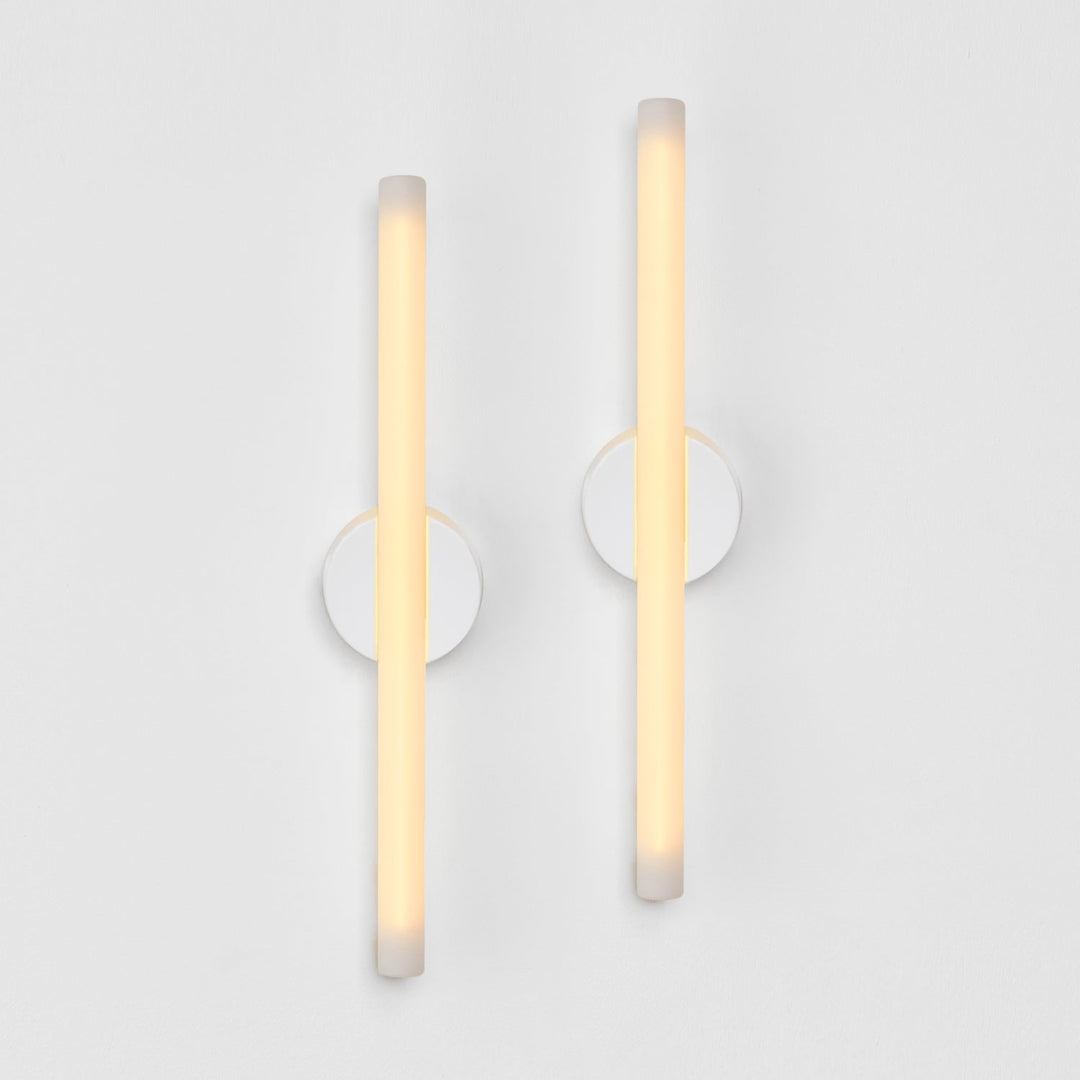 Modern frosted glass wall sconces with minimalist circular mounts, emitting warm ambient light.