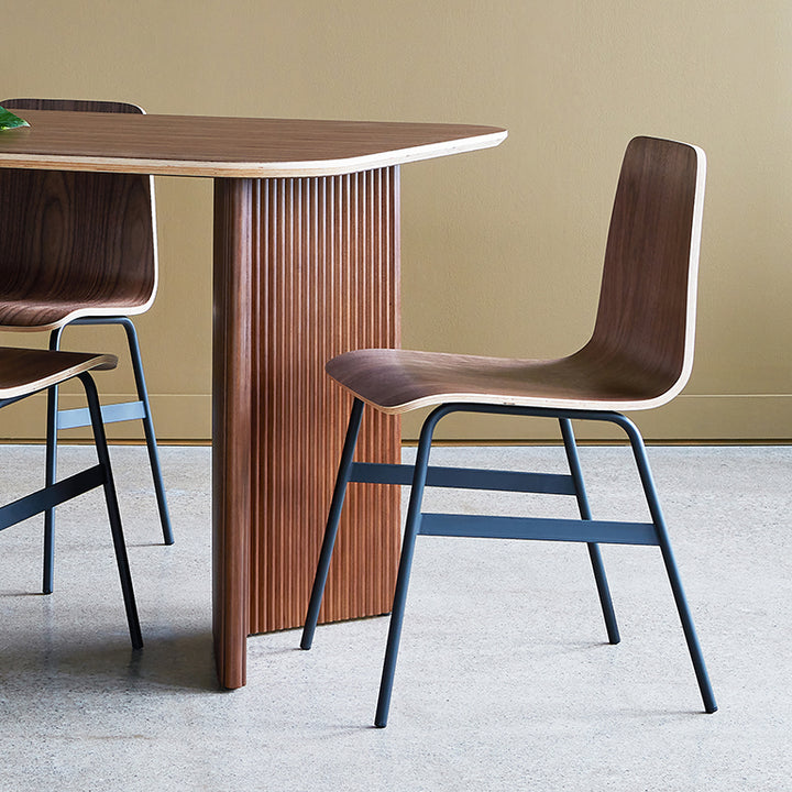 Walnut dining chair with steel legs, paired with fluted wood table