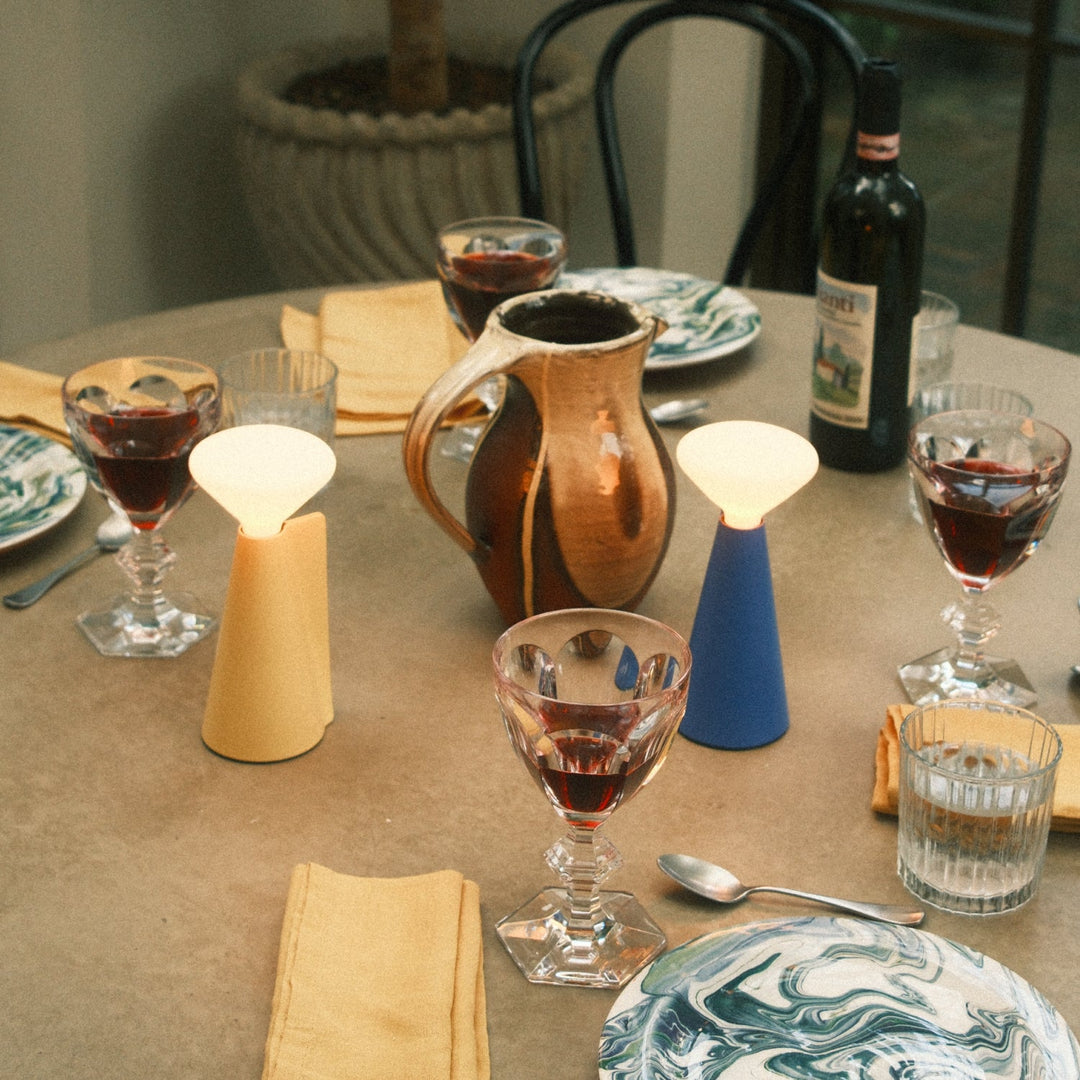 Ceramic pitcher and modern table lamps on a dining table with wine glasses and marbled plates