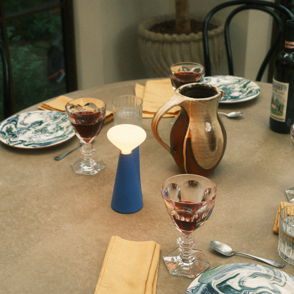 Blue ceramic table lamp with frosted glass shade, styled with marbled plates and crystal wine glasses