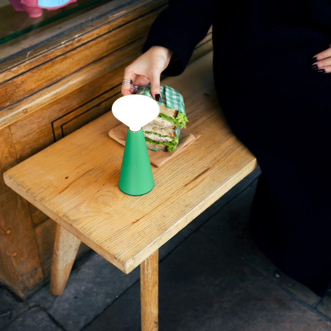 Green ceramic table lamp beside sandwich on rustic wooden table