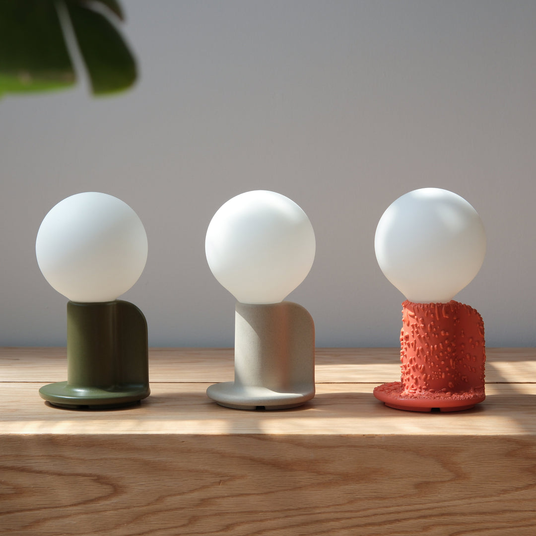 Minimalist ceramic table lamps with textured bases in olive, beige, and coral hues