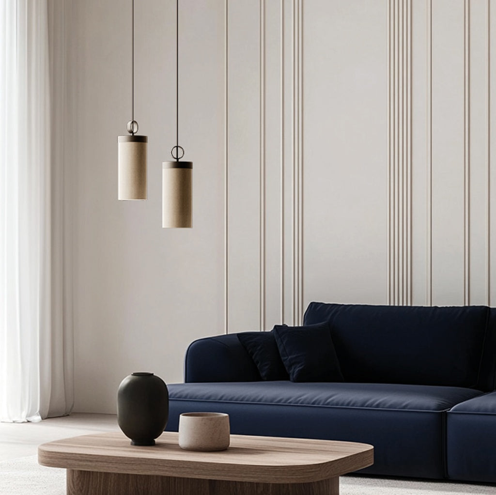 Two Nooi Pendant Lamps at staggered heights above a navy sofa and wooden coffee table