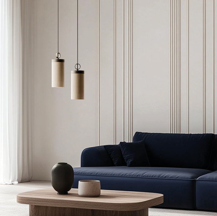 Two Nooi Pendant Lamps at staggered heights above a navy sofa and wooden coffee table