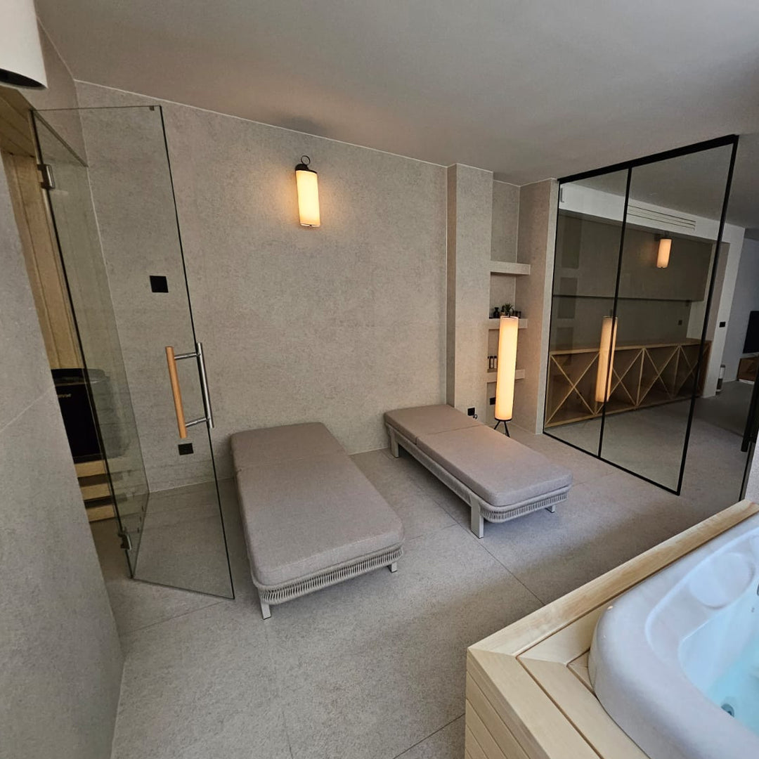 Modern indoor spa with hot tub, lounge chairs, and glass walls.
