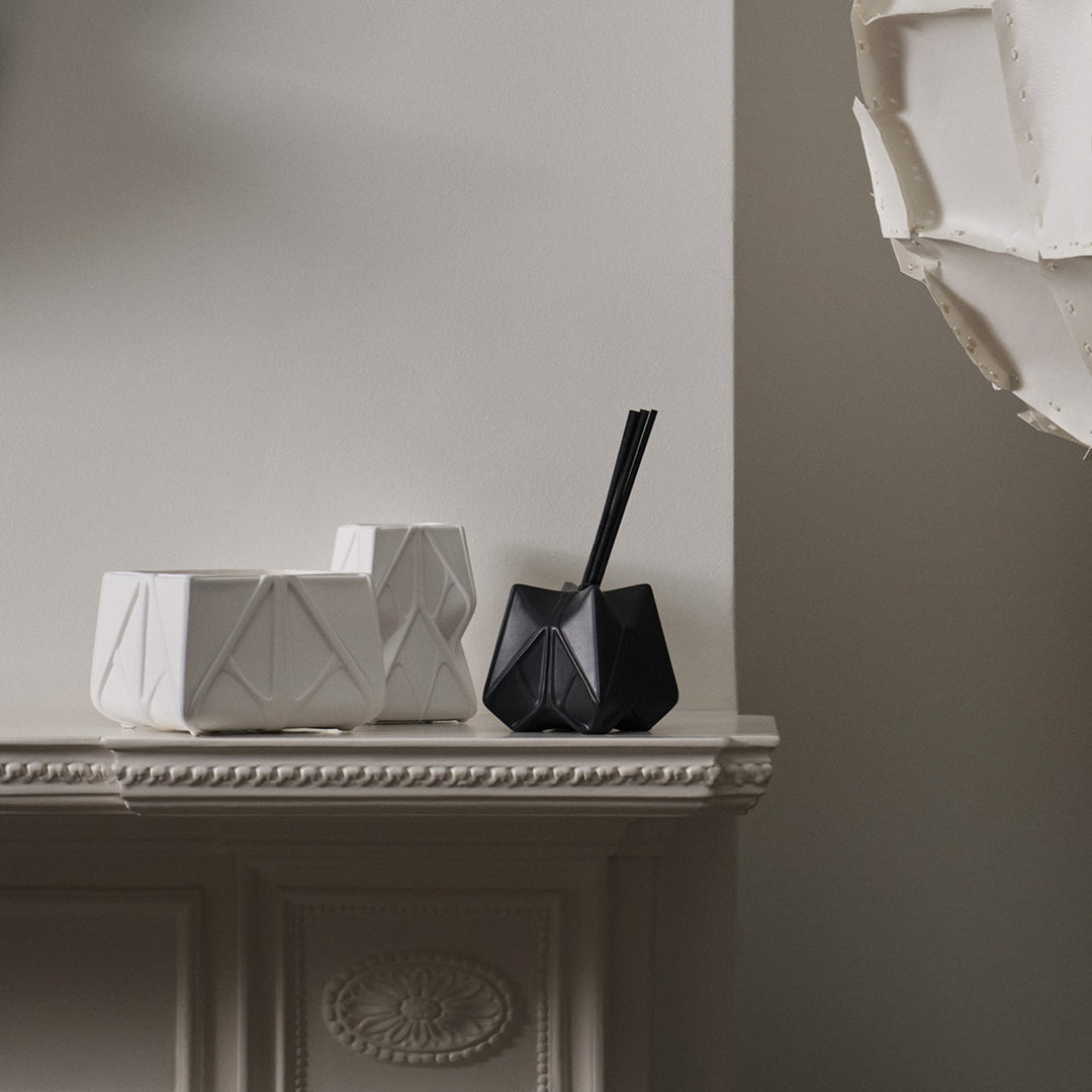 Prime Scented Candle — Large and Tall white candles with a black diffuser on a fireplace mantel