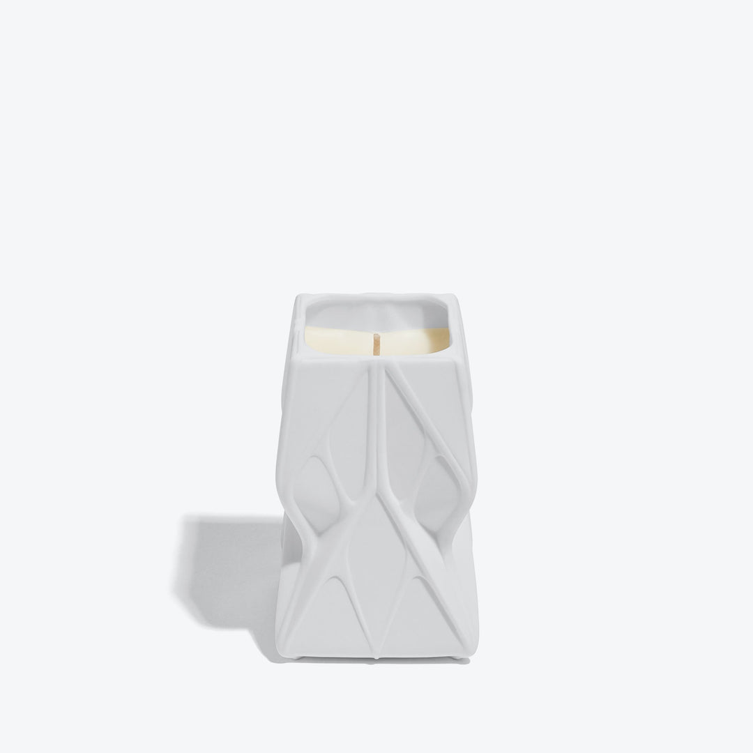 Prime Scented Candle — Tall white ceramic candle with faceted relief, front view on white