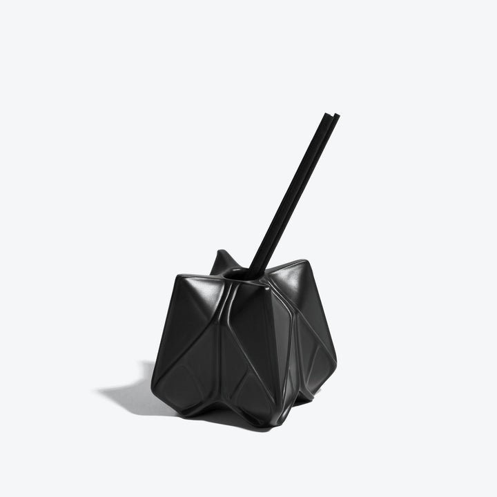 Prime Reed Diffuser — black matte faceted diffuser with reeds, three-quarter view on a white background