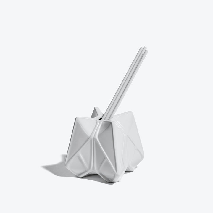Prime Reed Diffuser — white glossy faceted diffuser with reeds, three-quarter view on a white background