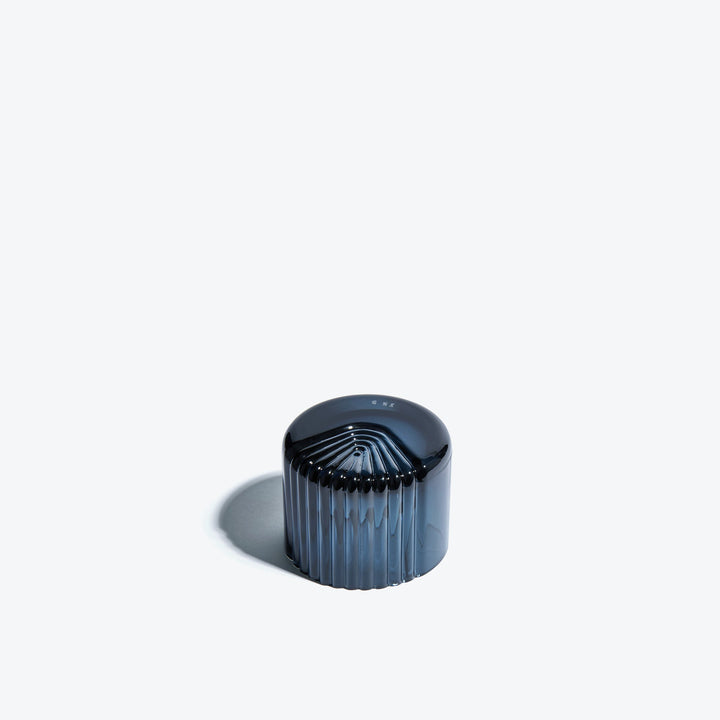 Pulse Tealight Holder X — dark blue tealight holder turned on its side showing the radiating ribs on its base