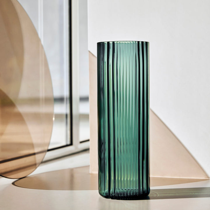Pulse Vase — tall Grey Green ribbed glass vase beside amber glass panels in sunlight, lifestyle view